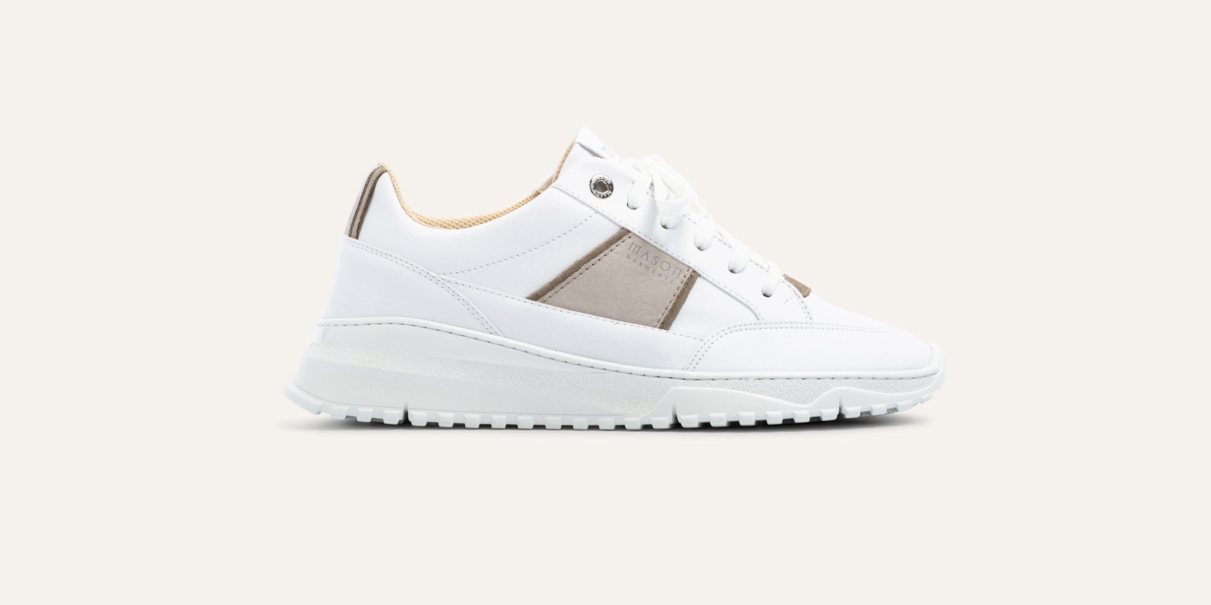 White sneaker with a beige panel on a light background