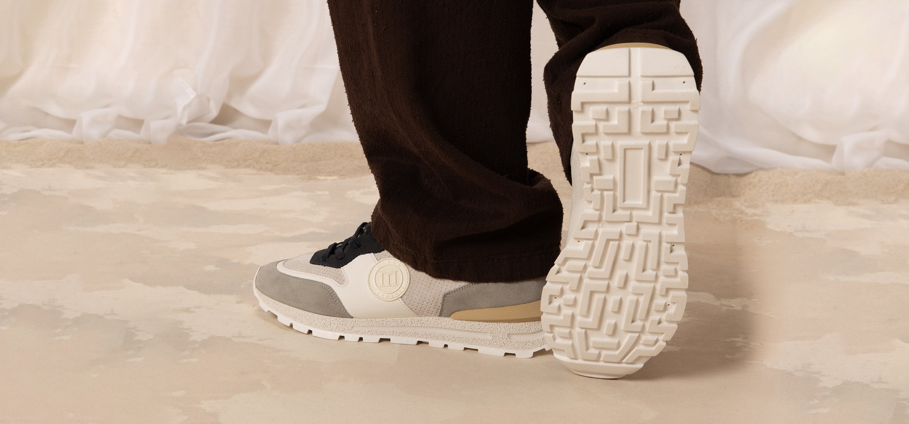 Close-up of a person wearing gray sneakers with white soles on a light-colored floor.