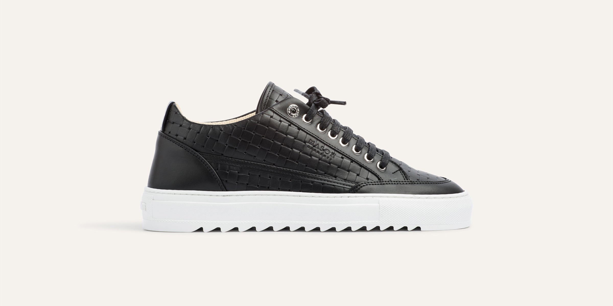 Black sneaker with white sole on a light gray background