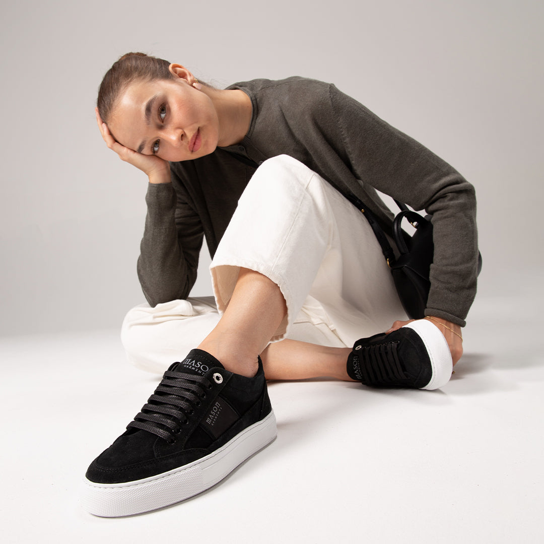 Woman wearing black sneakers with a white background