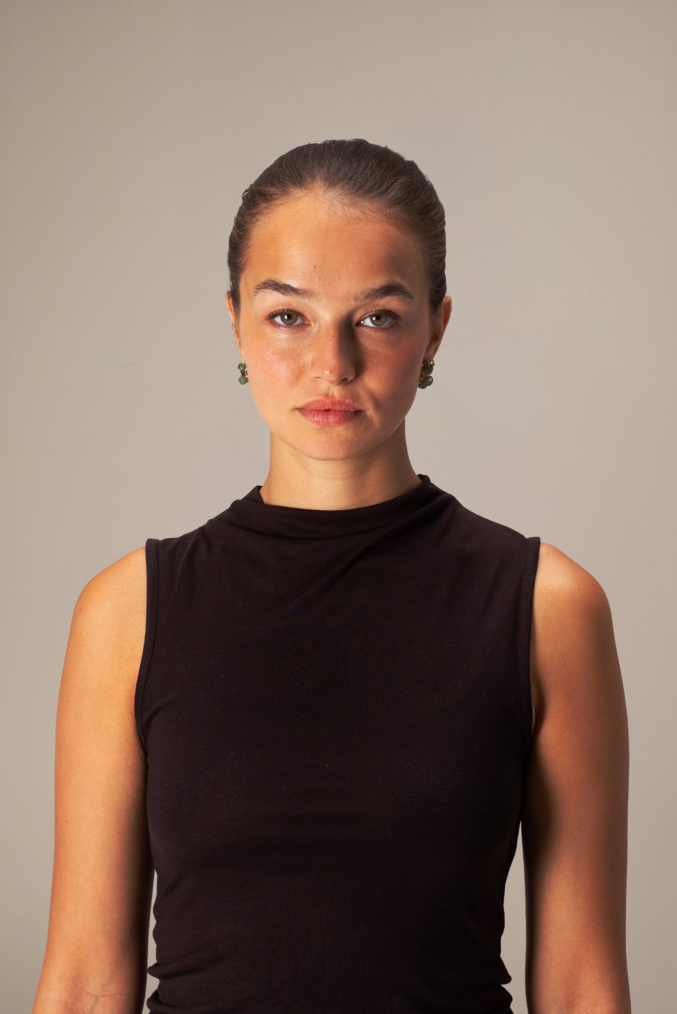 Woman wearing a brown sleeveless top against a plain background