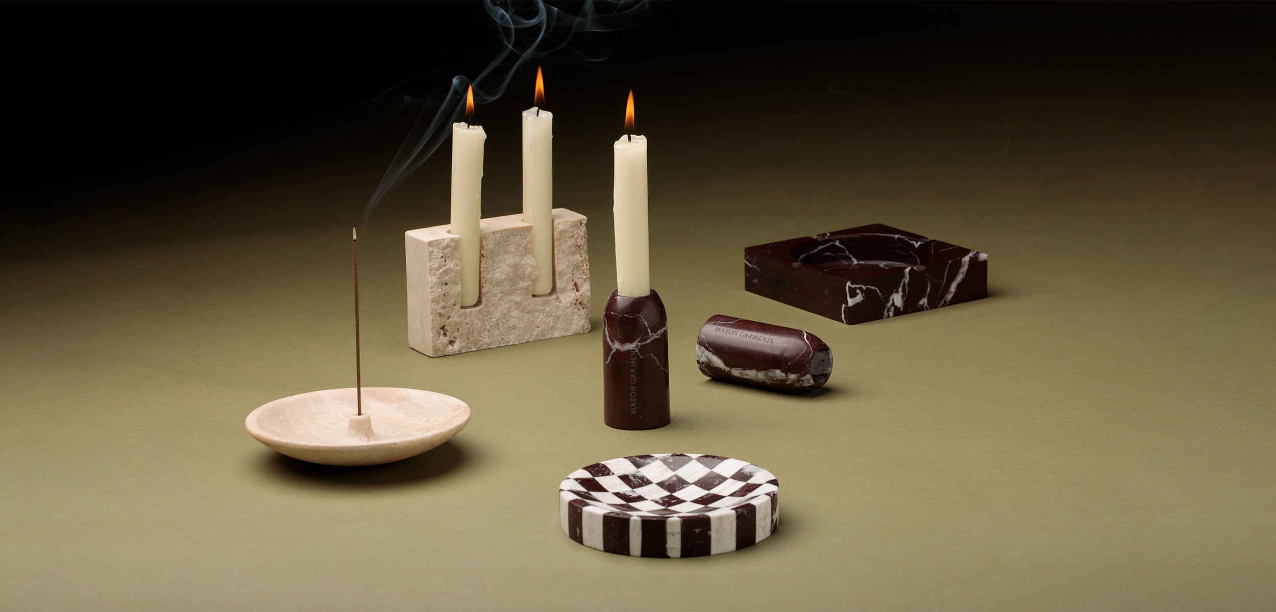 flatlay of home decor pieces (candle holders, trays) on green background