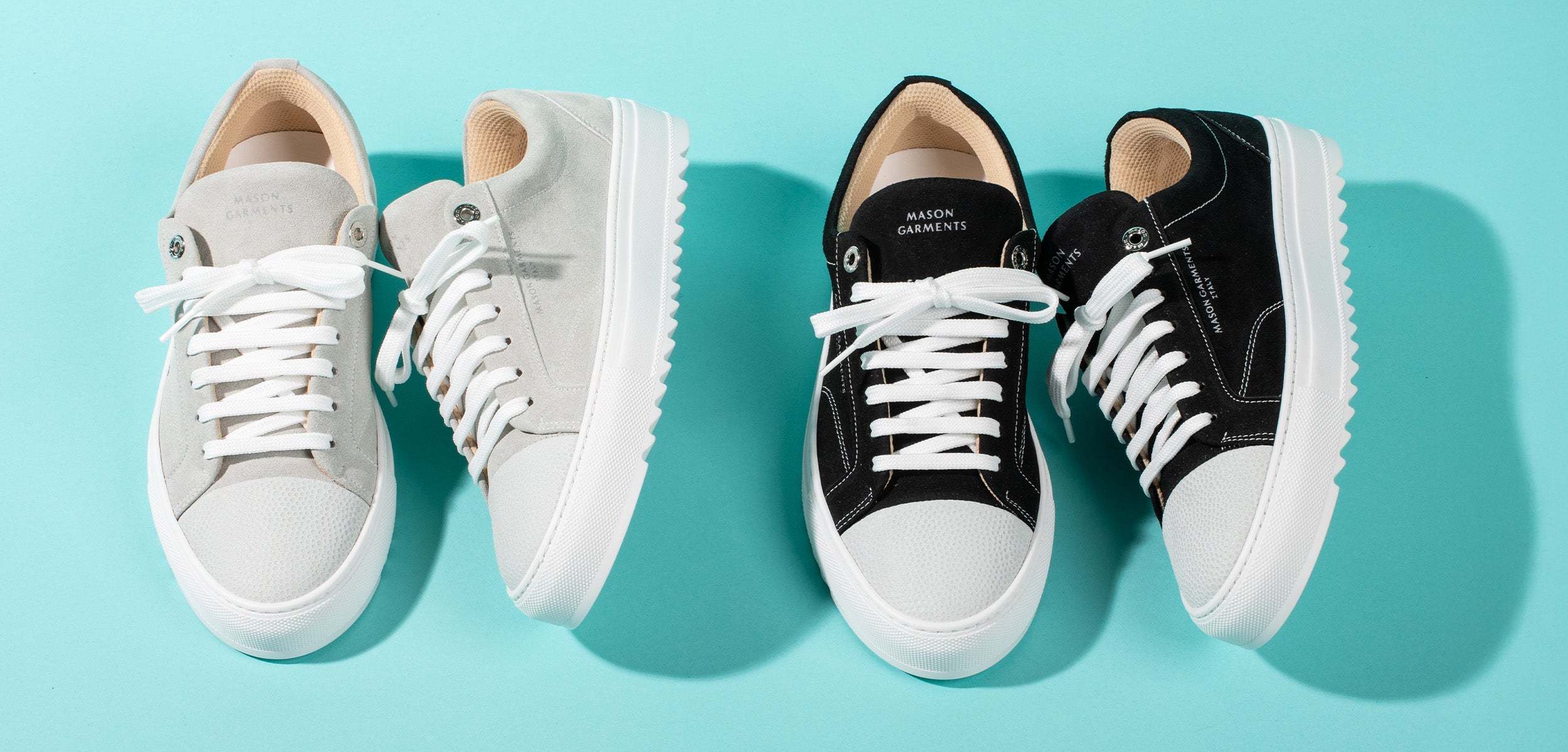 Two pairs of sneakers, one white and one black, on a light blue background.