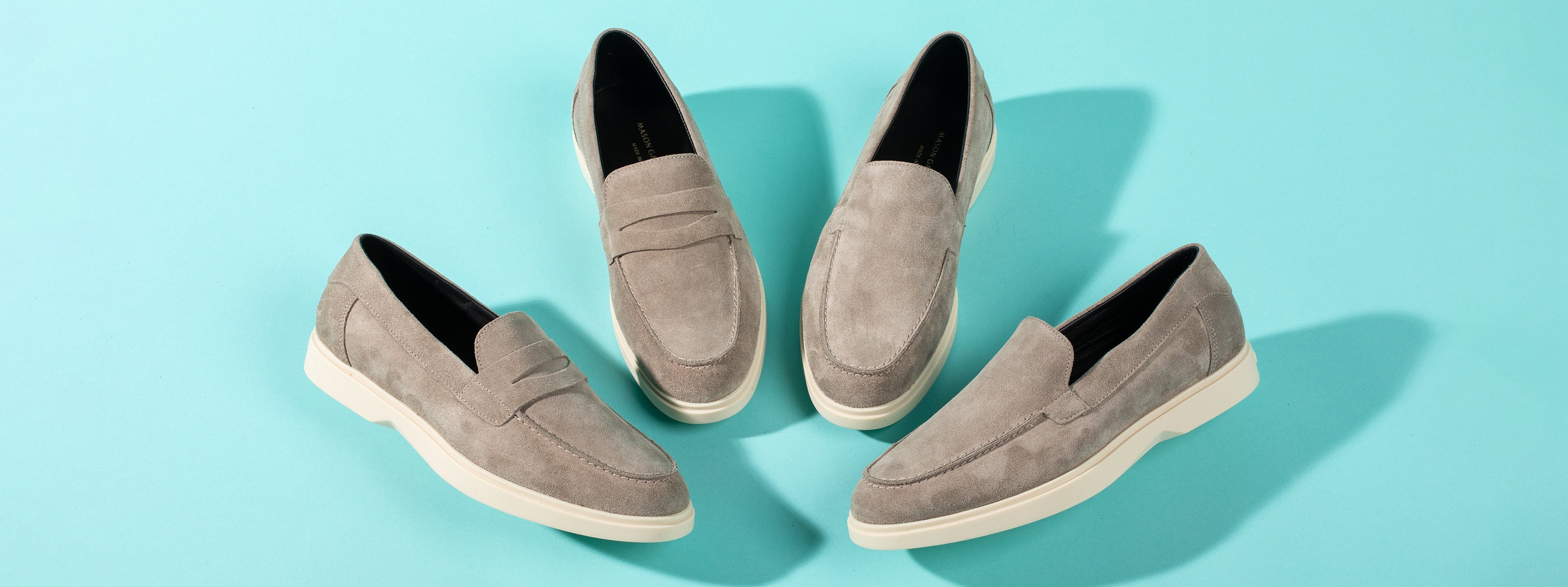 Flatlay of beige suede loafers on blue background